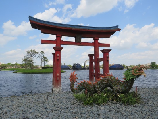 A Japanese gate and dragon sculpture in front of a lagoon. EPCOT's fireworks setups are visible on the horizon and would become important later.