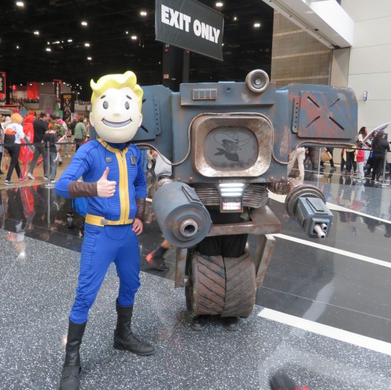 Two characters from Fallout video games: happy blonde mascot boy who gives everything a thumbs-up, and one-wheeled robot with no head and a black-and-white TV in its chest.